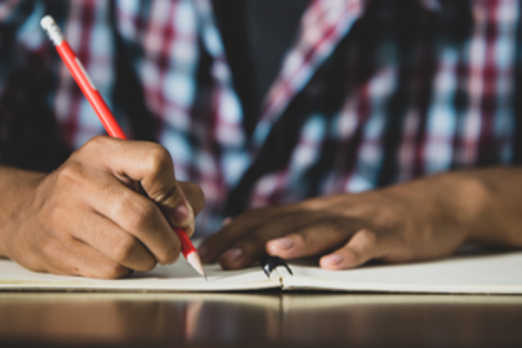 close da mão de um jovem escrevendo em um caderno