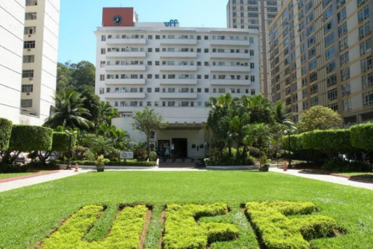 gramado verde em primeiro plano, ao fundo um prédio branco com um letreiro azul escrito uff