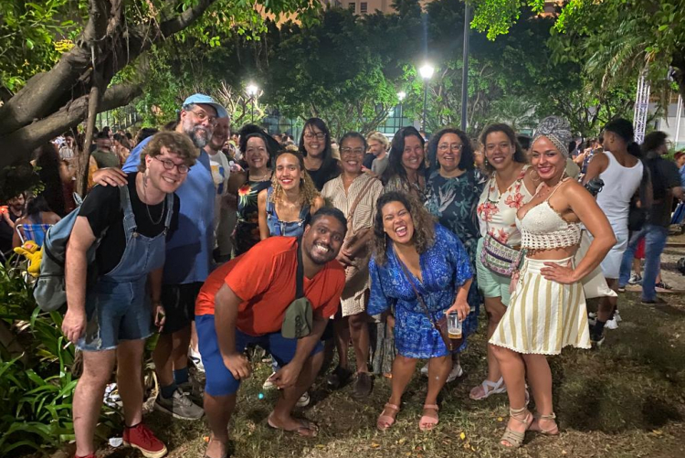 #ParaTodosVerem Alguns dos alunos do projeto estão reunidos em pé e posam sorridentes em um espaço arborizado