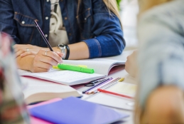 Estudantes em sala de aula, sentados e escrevendo em caderno de anotações