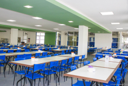 Foto do interior do restaurante universitário da UFF, com mesas brancas e cadeiras azuis dispostas pelo salão para a acomodação da comunidade universitária