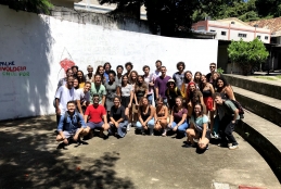 Muitos alunos de cinema reunidos em um pátio, cercado por escadas, num dia de sol
