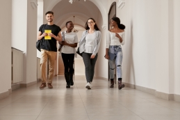 grupo de quatro estudantes multirraciais caminhando pelo corredor de uma faculdade