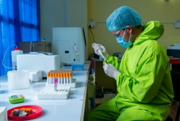 Homem em laboratório com EPI e pipeta na mão