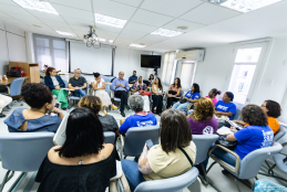 Foto tirada do fundo de uma sala com pessoas reunidas