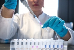Mulher manipulando instrumento de laboratório, inserindo um líquido em um tubo