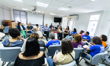 Foto tirada do fundo de uma sala com pessoas reunidas